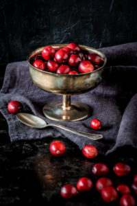 Stillleben mit frischen roten Cranberries in einer alten Silberschale vor dunklem Hintergrund Stillleben mit frischen roten Cranberries in einer alten Silberschale vor dunklem Hintergrund